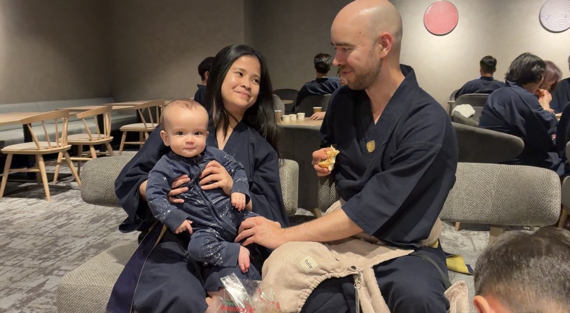 Mikko Sysikaski with his wife and their baby son, the three of them in yukata in a lounge in Japan.